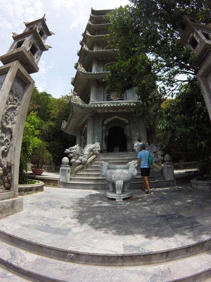 tall pagoda in marble mountains with stairs and dragons