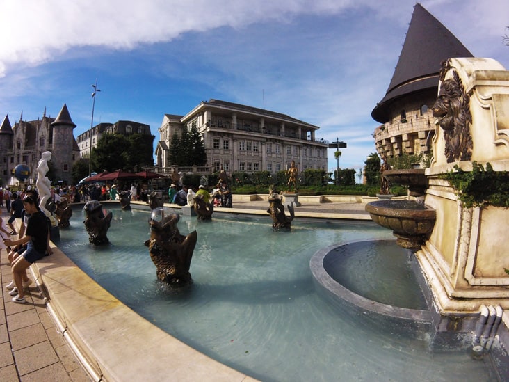 french style fountain in sun world theme park with french style buildings behind