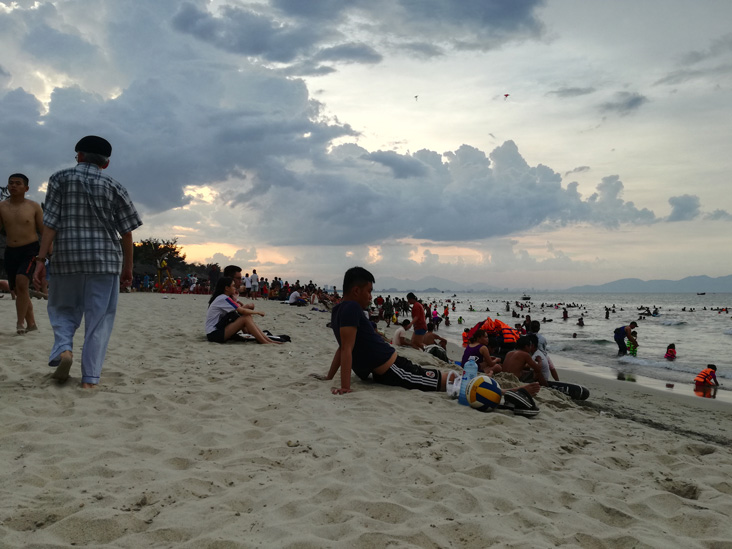 a group of people sitting on the sand in hoi an beach