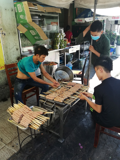 some guys cooking Nem Nuong outside the restaurante