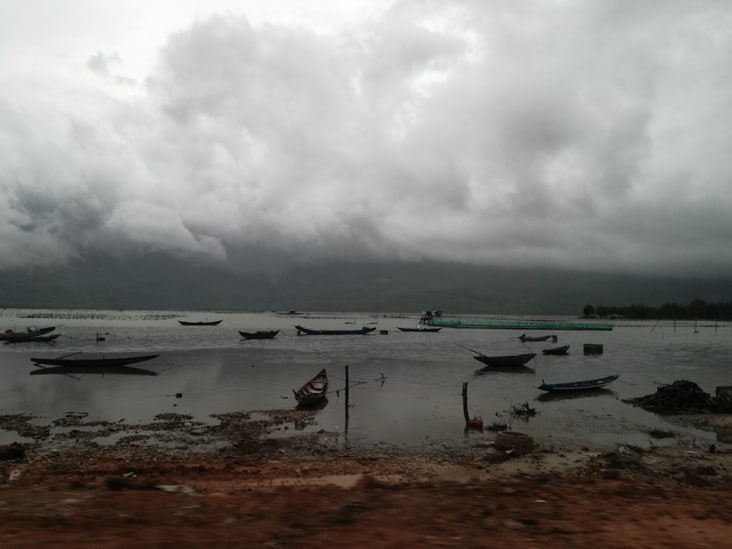 beatiful view of a river with boats and mountains behind in a cloudy day