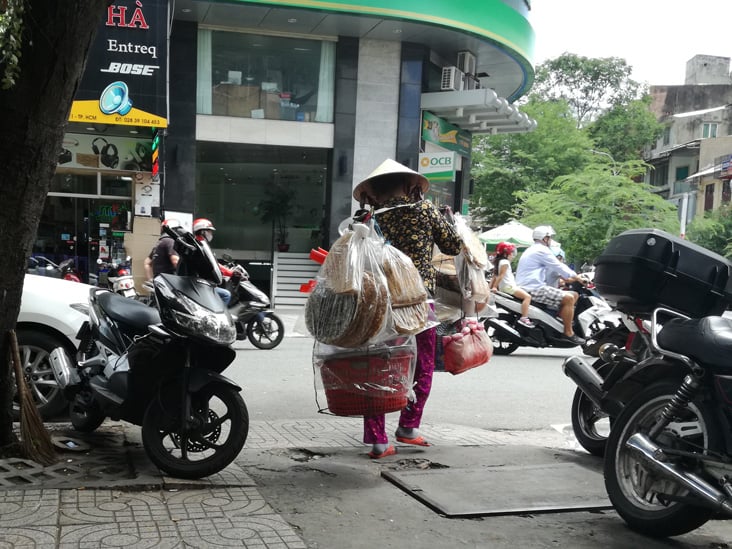 old woman wearing a traditional vietnamese hat catch the attention of tourist in ho chi minh