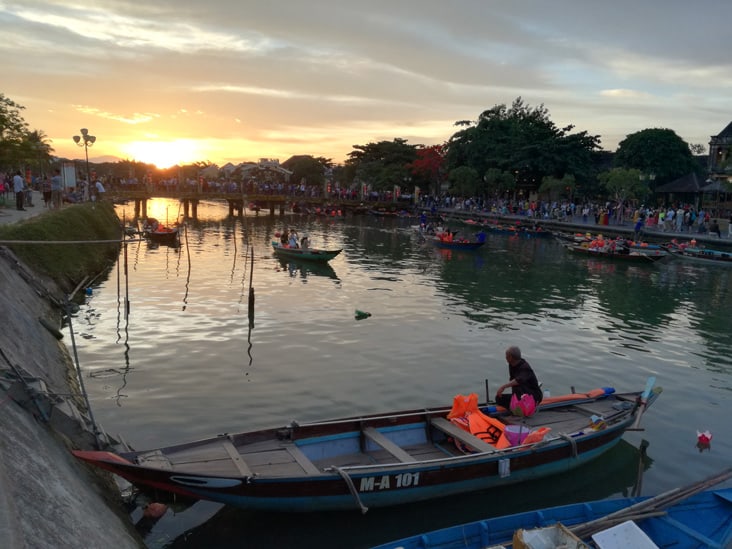 a very nice sunset in hoi an with some boats floating on the river